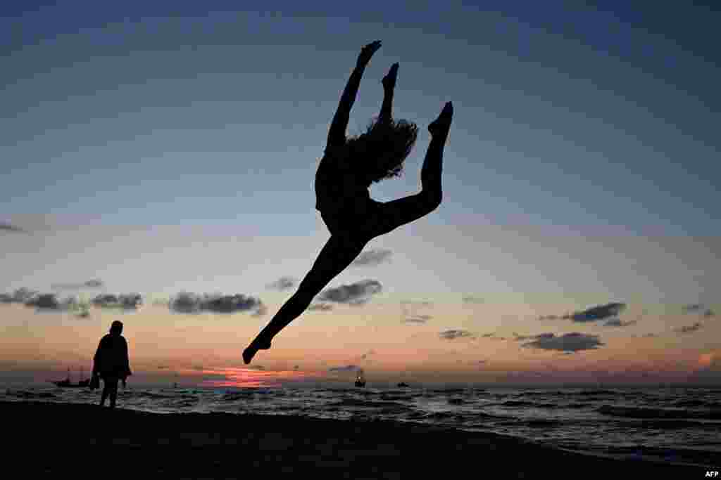 A member of the Grupa Magnifica acrobatics club poses for a photo on the Baltic Sea beach during sunset in the town of Leba, Pomeranian region, Poland, Aug. 6, 2024.