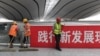资料照：北京大兴国际机场的工人在一幅“践行新发展理论”的标语旁工作。（2019年7月9日）