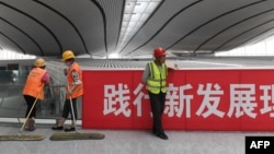 資料照：北京大興國際機場的工人在一幅「實踐新發展理論」的標語旁工作。 （2019年7月9日）