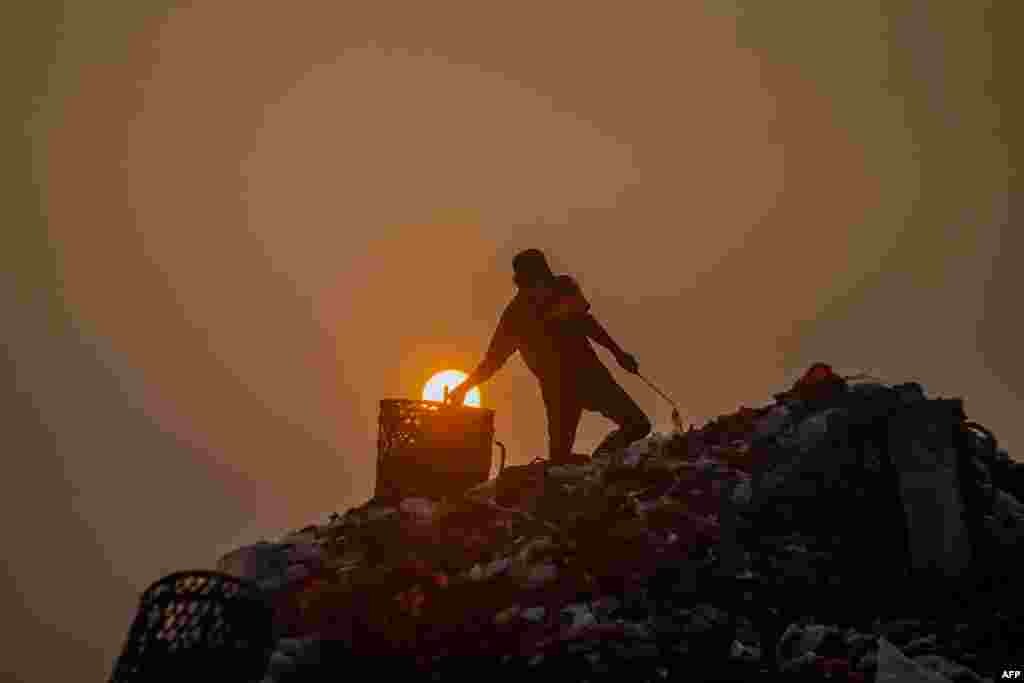 A man collects objects that can be resold after garbage trucks unload early in the morning at the Galuga landfill in Bogor, Indonesia.