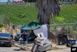 A homeless encampment sits next to the CA-110 freeway,, July 26, 2024, in Los Angeles