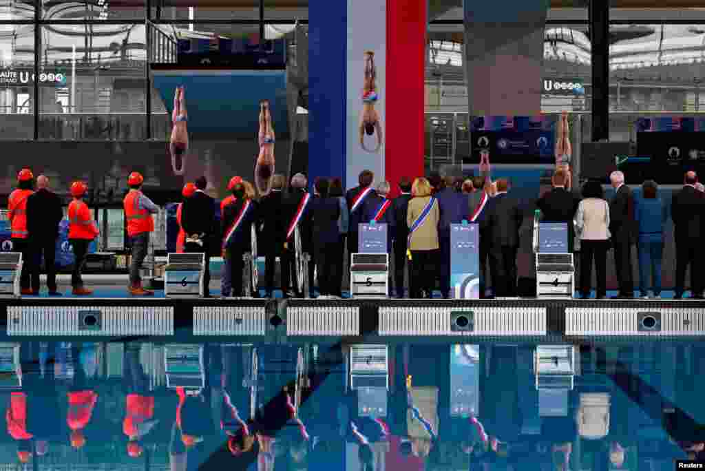 French President Emmanuel Macron, officials and workers look at a diving performance during the inauguration of the Olympic Aquatics Centre (CAO), in Saint-Denis, near Paris.