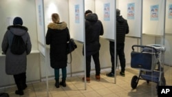 People fill their ballot papers at a polling station during parliamentary elections in Tallinn, Estonia, March 5, 2023.