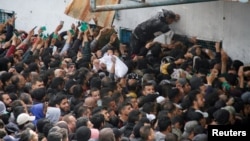 Palestinians gather to receive aid outside an UNRWA warehouse as Gaza residents face crisis levels of hunger, amid the ongoing conflict between Israel and Hamas, in Gaza City, March 18, 2024.