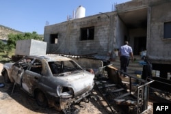 A Palestinian inspects the damage to a home in the village of Al-Mughayyir near Ramallah in the Israeli-occupied West Bank on April 13, 2024, after an attack by Israeli settlers on the village.