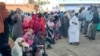 (FILE) People displaced by the ongoing conflict in Sudan between the army and paramilitaries wait to receive aid from a charity in Sudan.