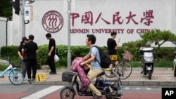 People past near the logo for Renmin University outside the main campus in Beijing, July 22, 2024. A PhD student at Renmin University accused her supervisor of molesting her and taking revenge after being rejected. 