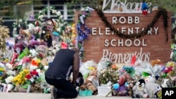FILE - Reggie Daniels pays his respects a memorial at Robb Elementary School, June 9, 2022, in Uvalde, Texas, created to honor the victims killed in the school shooting. 