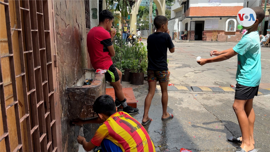 Mientras llega la hora de la tradicional batalla entre las barriadas, los chicos van afinando entre ellos su puntería. Unos se echan agua con un balde, otros usan una pistola de juguete. Más allá, en una zona seca y segura, los adultos observan.