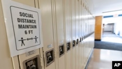 FILE - A sign about social distancing is posted on student lockers at a school in Baldwin, N.Y., on Aug. 28, 2020.