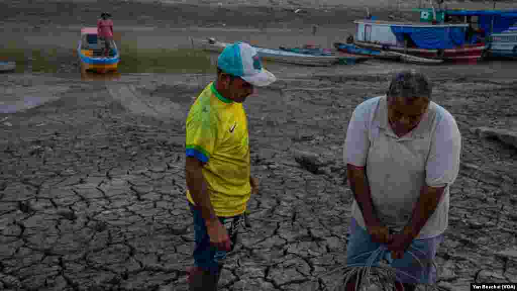 Pescadores se preparam para retirar um pequeno barco do leito seco do rio Puraquequara para encontrar um ponto com acesso ao rio Amazonas para continuar seu trabalho, 3 de outubro de 2023.