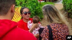 FILE - Jordan Ruidas holds her daughter as she speaks with visitors Dec. 1, 2023, in Lahaina, Hawaii.
