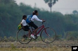 FILE - School children ride a bicycle to school on the outskirts of Phnom Penh, Cambodia, Wednesday, Feb. 1, 2023.