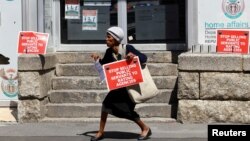 FILE: A member of the South African public sector union holds a placard outside the Home Affairs office during a protest over wage disputes and other work issues in Cape Town, March 13, 2023.