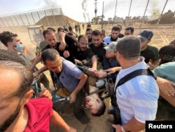 Palestinci vuku beživotno telo čoveka za kog kažu da je izraelski vojnik ubijen u napadu militanata Hamasa na južni Izrael, na granici Izraela i Gaze, 7. oktobra 2023.