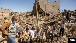 Volunteers watch as a digger moves rubble of collapsed houses in Tafeghaghte, 60 kilometers (37 miles) southwest of Marrakesh, Sept. 10, 2023, two days after a devastating 6.8-magnitude earthquake struck the country.