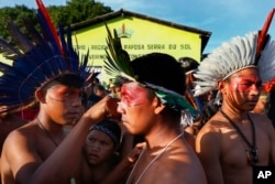 A Macuxi Indigenous man paints the face of another at the Caracarana Lake Regional Center in Normandia, on the Raposa Serra do Sol Indigenous reserve in Roraima state, Brazil, Monday, March 13, 2023. (AP Photo/Edmar Barros)