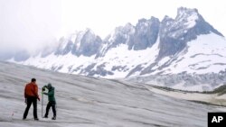 Team members of ETH (Swiss Federal Institute of Technology) glaciologist and head of the Swiss measurement network 'Glamos', Matthias Huss, drill holes into the Rhone Glacier to take measurements near Goms, Switzerland, June 16, 2023.