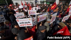 FILE: Demonstrators lift placards during an anti-government rally called for by the powerful trades union federation UGTT in Tunis. Taken March 4, 2023
