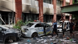 Warga berjalan di samping mobil-mobil yang rusak di Kantor Polisi Mohammadpur, setelah pengunduran diri Perdana Menteri Bangladesh Sheikh Hasina, di Dhaka, Bangladesh, pada 6 Agustus 2024. (Foto: REUTERS/Mohammad Ponir Hossain)