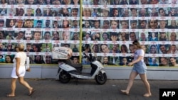 People walk past posters of Israelis held hostage by Palestinian militants in Gaza since the October 7 attacks, in Tel Aviv on Aug. 11, 2024.