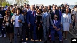El presidente Joe Biden habla con la congresista Terri Sewell, al centro, y el reverendo Al Sharpton después de cruzar el puente Edmund Pettus en Selma, Alabama, el 5 de marzo de 2023, para conmemorar el 58.º aniversario del "Domingo Sangriento".