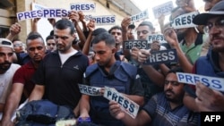 Mourners and colleagues holding "press" signs surround the body of Al Jazeera journalist Ismail al-Ghoul, killed along with cameraman Rami al-Rifi in an Israeli strike during their coverage of Gaza's Shati refugee camp, on July 31, 2024.