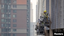 FILE - Men work at the construction site of an apartment building in Beijing, July 29, 2023. 