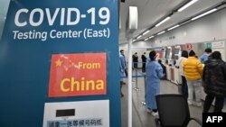 Health workers guide travelers arriving from China at a COVID-19 testing center at Incheon International Airport, west of Seoul on Jan. 3, 2023.