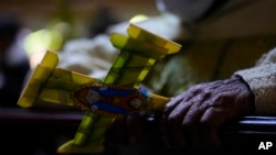 Una mujer sostiene una hoja de palma en forma de cruz durante la Misa del Domingo de Ramos en una iglesia en El Alto, Bolivia, el domingo 2 de abril de 2023.