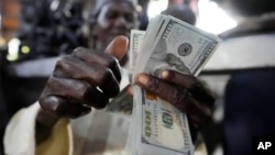 A man counts U.S. $100 bills at the craft and art market in Lagos, Nigeria, Aug. 16, 2023. Many countries are fed up with the dominance the U.S. dollar.