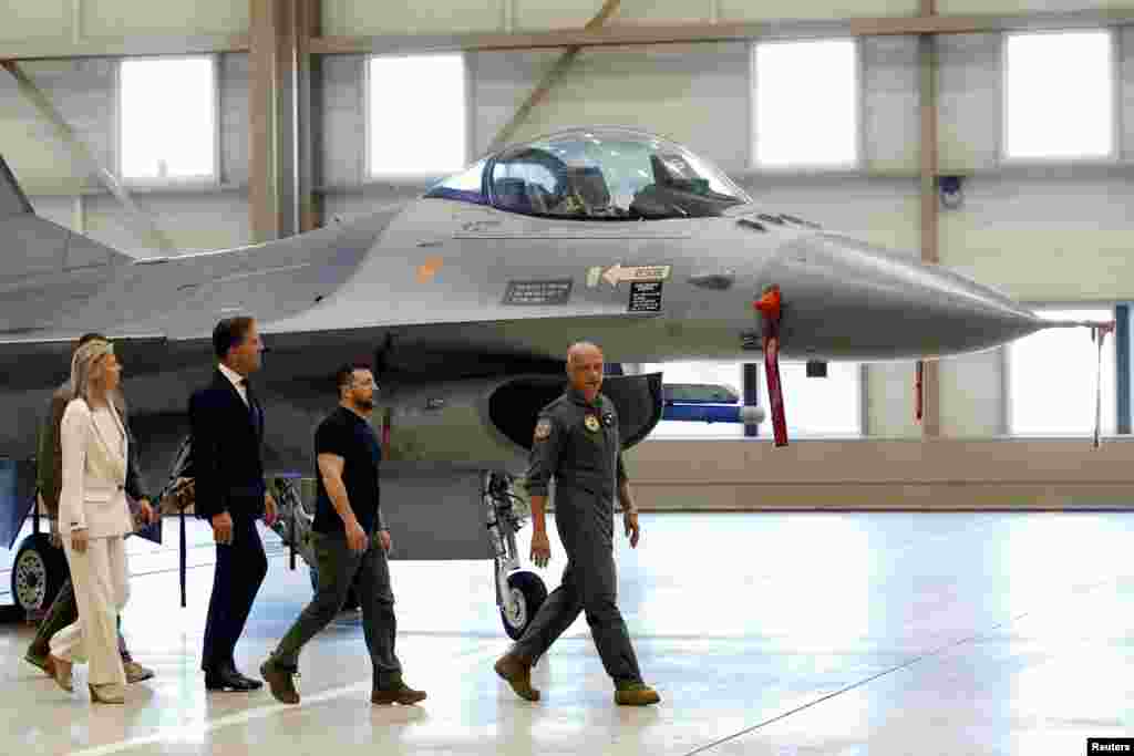 Ukrainian President Volodymyr Zelenskiy and Dutch Prime Minister Mark Rutte walk near an F-16, in Eindhoven, Netherlands.