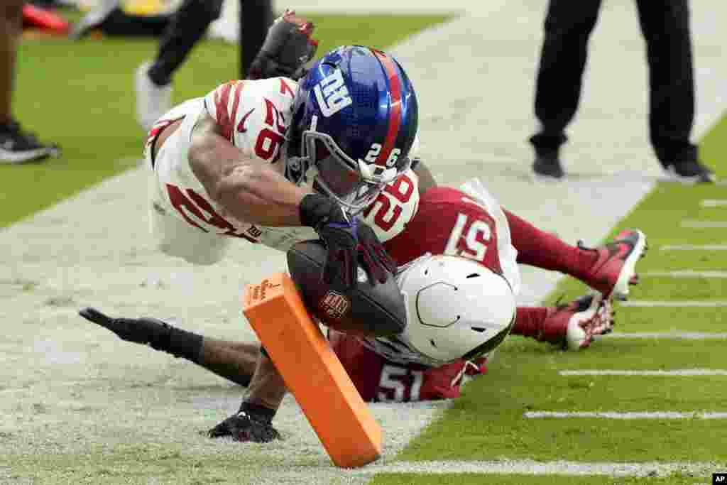 New York Giants running back Saquon Barkley (26) dives into the end zone for a touchdown as Arizona Cardinals linebacker Krys Barnes (51) defends during the second half of an NFL football game, Sept. 17, 2023, in Glendale, Arizona.