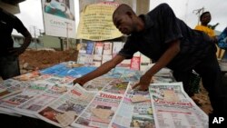 A man arranges local newspapers with preliminary presidential election results on a street in Lagos, Nigeria, Monday, Feb. 27, 2023.