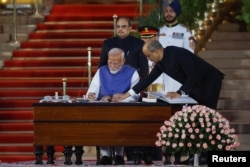 India's Prime Minister Narendra Modi signs documents after taking his oath during a swearing-in ceremony at the presidential palace in New Delhi, June 9, 2024.
