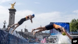 FILE - Athletes dive back into the Seine River for the second lap of the swim portion at the men's individual triathlon competition at the 2024 Summer Olympics, in Paris, France, July 31, 2024. 