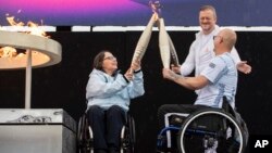 British Paralympians Helene Raynsford, left, and Gregor Ewan light the Paralympic Flame in Stoke Mandeville, widely considered the birthplace of the Paralympic Games, England, Aug. 24, 2024. 