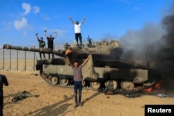 Palestinci slave na uništenom izraelskom tenku, nakon napada palestinskih militanata na Izrael, na granici Izralea i Gaze, 7. oktobra 2023.