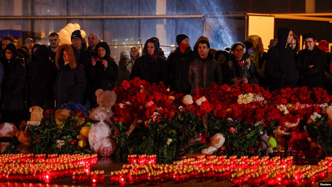 Orang-orang berdiri di depan lilin yang menyala di luar tempat konser Balai Kota Crocus pada hari berkabung yang diumumkan setelah insiden penembakan maut di pinggiran Moskow, Rusia, 24 Maret 2024.