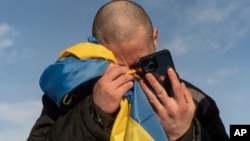 FILE - A recently swapped Ukrainian prisoner of war cries while calling his relatives after a prisoner exchange on the Ukrainian-Russian border, on Jan. 31, 2024. Russian forces are accused of kidnapping and torturing civilians they deem dangerous.