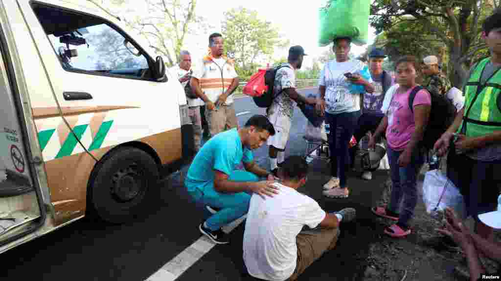 Un paramédico conversa con un migrante que se sintió mal durante su viaje en caravana. 