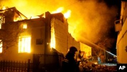 In this photo provided by the Ukrainian Emergency Service, firefighters work on the scene of a burning building after a Russian drone attack in Dublyany, Lviv region, Ukraine, Jan. 1, 2024. (Ukrainian Emergency Service via AP)