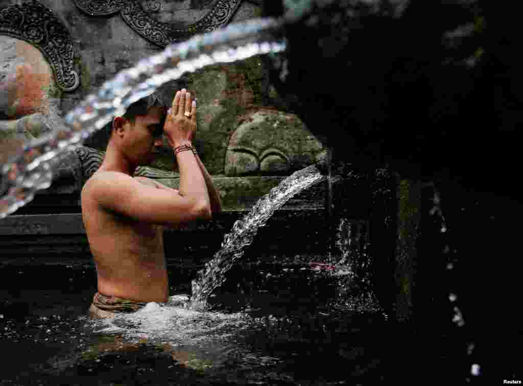 A Balinese Hindu prays before taking a bath during a cleansing ritual called Banyu Pinaruh, which is believed to purify their body and soul, at Tirta Empul temple&#39;s holy spring in Gianyar, Bali, Indonesia.