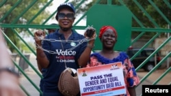 A woman shows her hands in chains while another holds a placard during a protest against legislative bias against women, on the International Women's Day, in Abuja, Nigeria March 8, 2022.
