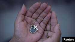 An Ecuadorean asylum seeker who said she was kidnapped and sexually trafficked near the US-Mexico border holds a necklace that she received as a gift, as she speaks with reporters in New Jersey, on Aug. 18, 2023.