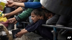 Palestinians reach for food in Rafah, Gaza Strip, Dec. 21, 2023. International aid agencies say Gaza is suffering from shortages of food, medicine and other basic supplies as a result of the 2-1/2-month war between Israel and Hamas.