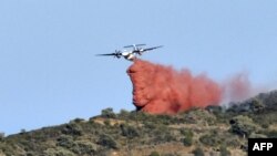 A plane drops fire retardant over a forest fire on a hill near the village of Banyuls-sur-Mer, southwestern France on April 16, 2023.