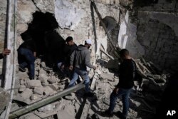 Palestinians inspect the ruins of a militant hideout destroyed during a raid by Israeli forces in the Old City of Nablus in the West Bank, Wednesday, Feb. 22, 2023.