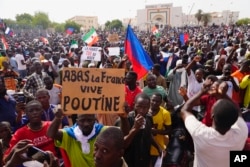 Nigeriens participate in a march called by supporters of coup leader General Abdourahamane Tchiani in Niamey on July 30, 2023. The sign reads: "Down with France, long live Putin."