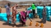 (FILE) Sudanese refugees displaced by the conflict in Sudan gather to receive food staples from aid agencies in eastern Chad, March, 2024. 